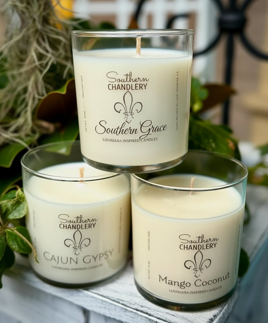 Three candles from Southern Chandlery with labels on a surface with greenery in the background