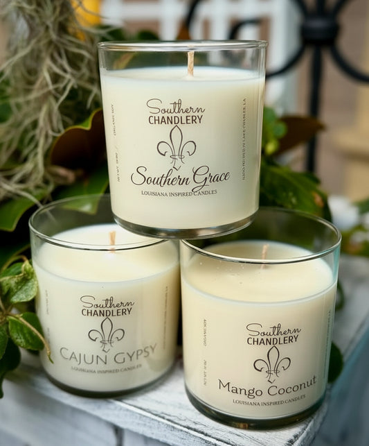 Three candles from Southern Chandlery with labels on a surface with greenery in the background